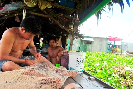 Anh Út Lời tranh thủ giờ nghỉ vá vội dàn lưới bị rách (Ảnh: Nguyễn Công Minh)