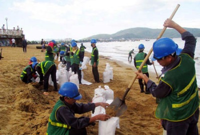 Công nhân Công ty TNHH Môi trường và đô thị Quy Nhơn thu gom váng dầu tại bãi biển. (Ảnh: CTV/CAND)